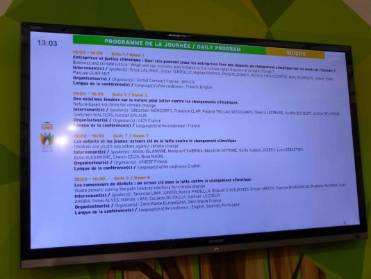 Where next ? Visitors gather in front of the screen to look at the programme. The session 'Children and Young people : key actors in fighting climate change' takes place in conference room 7 at 15h00. A great opportunity to discover the incredible work carried out by young people !