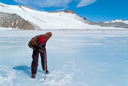 Jeroen Van Wichelen drills a hole in the frozen surface of a lake