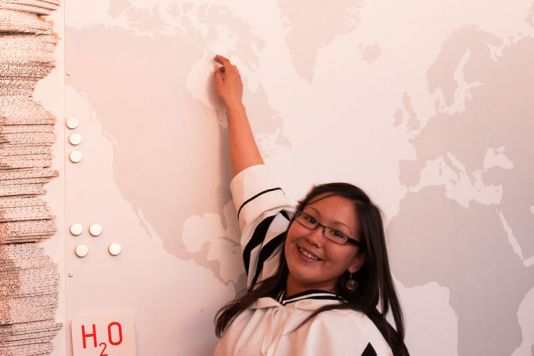 Une étudiante pointe sur une carte du monde la région d'où elle vient au Canada.