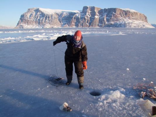 Pêche traditionnelle sur la banquise arctique en février, ce qui nécessite pour le pêcheur de superposer les couches de vêtements!