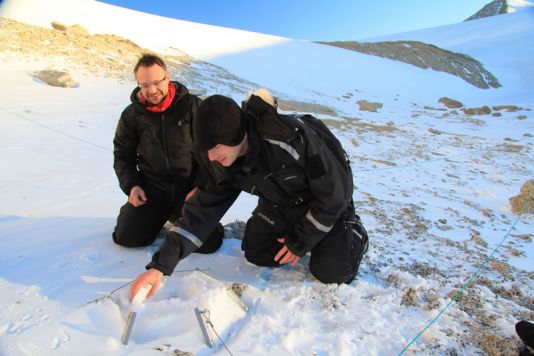 Sommige dataloggers zijn bedolven onder sneeuw. Leerkracht Koen Meirlaen helpt Elie met het weghalen van de sneeuw.