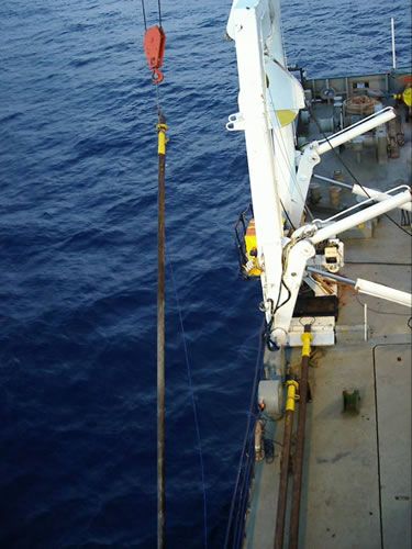 Calypso-cores are large-diameter (15 cm) steel pipes with an extra plastic liner in which the sediment is caught. Here, a core is taken out of the water, after the 8 tonne weight has been removed. The white colour on the core barrel already indicates a successful penetration of the seafloor (muddy sediment usually sticks to the outside of the core).