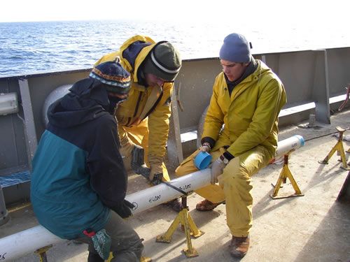 Les scientifiques à bord du Marion Dufresne découpent une carotte en tronçons.