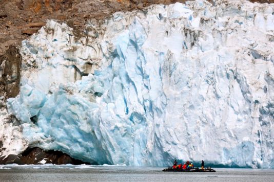 Studenten en staf cruisen tussen de ijsbergen met zicht op een gletsjer.