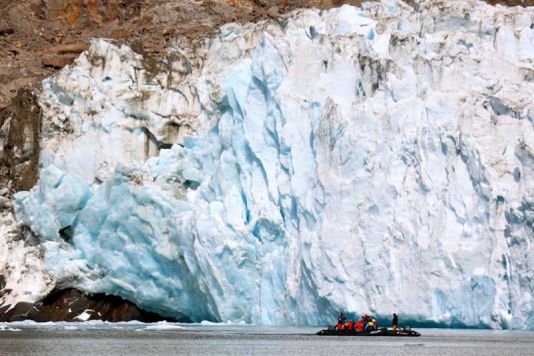 Les étudiants et l'équipe en croisière entre les icebergs, avec vue sur un glacier.