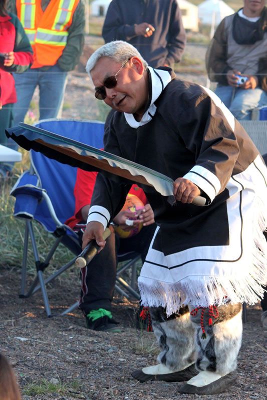 Un ancien Inuit joue du tambour Inuit autour du feu de camp.